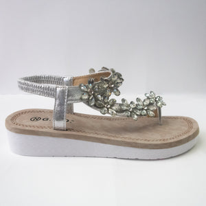 A silver toe-ring sandal with crystal flower embellishments trailing from the toe-ring to upper-strap.