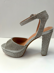 High heeled party and evening shoe with crystal embellishments. Open-toed sandal. Platform with ankle strap. Good for parties and formal occasions. Evening shoe. Party shoe. Comes in silver color.
