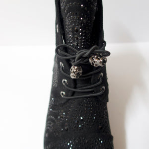 Black ankle booties with skull shoelaces and crystal embellishments. Slight heel. Black crystal embellished upper. Shoelaces with a skull aglet.