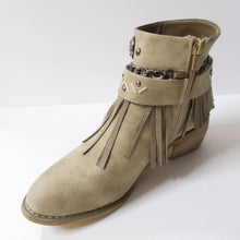 Load image into Gallery viewer, Tan/beige ankle booties with fringe design and embellished strap upper. Suede-like material. Slight heel. Decorated upper with a chain, embellished strap, and fringe. Inner side-zipper.
